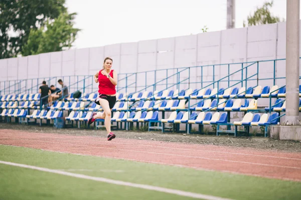 Běžkyně běhání na stadionu, žena atletka běhání a cvičení venku, sport a fitness koncept. Mladá žena ve sportovním tréninku na stadionu. Sportovní životní styl téma — Stock fotografie