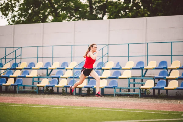 Γυναίκα τρέχει στο στάδιο. Νεαρή γυναίκα τρέχει στην πίστα του σταδίου. Η έννοια της επίτευξης στόχου. Γυμναστική Τζόγκινγκ Γυμναστική στο γήπεδο. Θέμα ευεξίας. Αθλητική προπόνηση καρδιο για την επιτυχία απώλειας βάρους — Φωτογραφία Αρχείου
