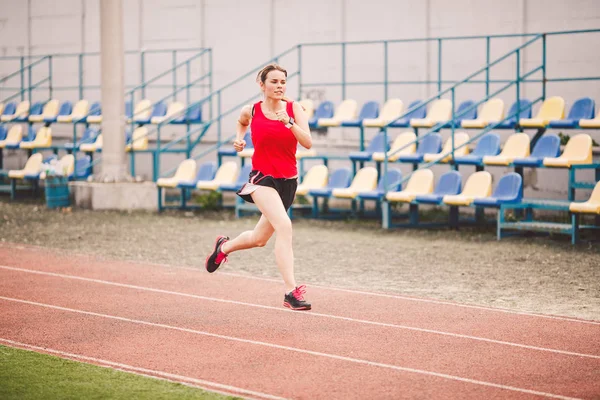 Běžkyně běhání na stadionu, žena atletka běhání a cvičení venku, sport a fitness koncept. Mladá žena ve sportovním tréninku na stadionu. Sportovní životní styl téma — Stock fotografie