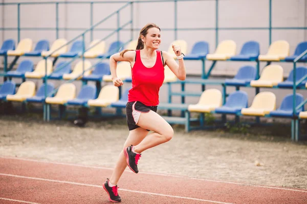 Female runner jogging on stadium track, woman athlete running and working out outdoors, sport and fitness concept. Young woman in sportswear training on a stadium. Sport lifestyle topic — 스톡 사진