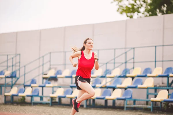 Woman Running At Stadium. Young woman running during on stadium track. Goal achievement concept. Fitness Jogging Workout on ballpark. Wellness theme. Sporty training cardio for weight loss success — 스톡 사진