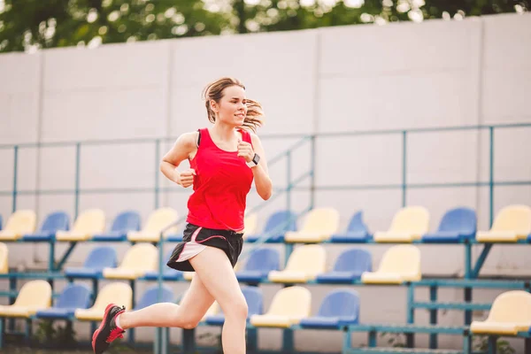 Stadyum pistinde koşan bayan koşucu, koşan ve dışarıda koşan kadın sporcu, spor ve fitness konsepti. Spor giyimli genç bir kadın stadyumda antrenman yapıyor. Spor yaşam tarzı konusu — Stok fotoğraf