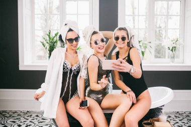 Spa'daki mutlu arkadaş grubunu gösteren resim. kafalarında havlu olan kızlar eğlenir ve evde selfie çekerler. Dostluk, kozmetik, pijama partisi konsepti. Otelde bir gelin ile Hen parti