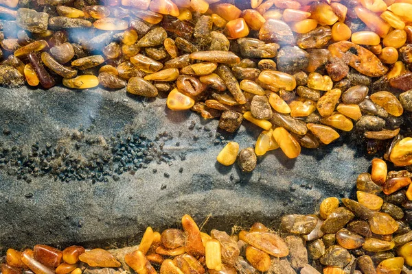 Amber grains with backlight illumination as texture or background. heap of amber stones backlightet glowing. Small raw amber. amber stones rectangular lie on a flat surface