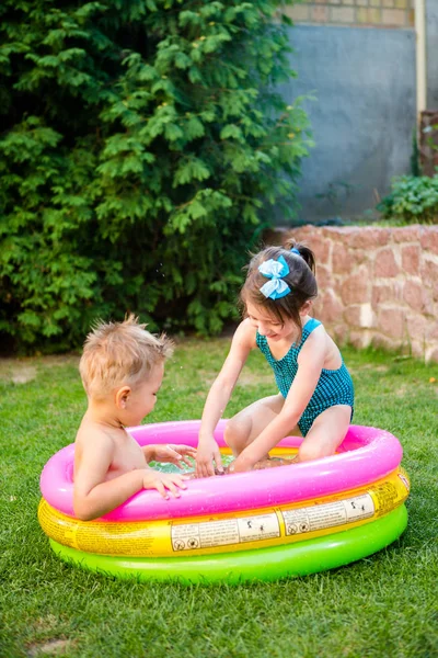 Niños divirtiéndose nadando en la piscina del patio trasero. Niños divertidos bañándose en la piscina al aire libre. Niños felices jugando en el agua. bebés divirtiéndose en el jardín piscina infantil —  Fotos de Stock