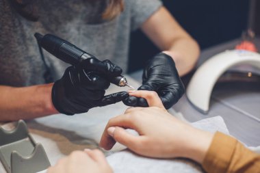 Güzellik Salonu, Manikür, Çivi Cila Prosedürü. Güzellik salonunda elektrikli makine kullanan profesyonel donanım manikürü. Usta manikür sırasında ojeli elleri kesmek için elektrikli makine kullanıyor.