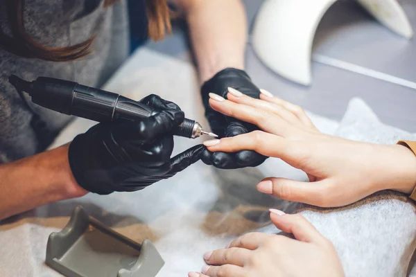 Beautician Salon, Manicure, Nails Polish Procedure. Professional hardware manicure using electric machine in beauty salon. master uses an electric machine to remove nail polish hands during manicure