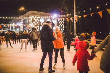 Beautiful Couple Ice Skating In City Centre. Young couple skating at a public ice skating rink outdoors. Theme ice skating rink and loving couple. Amazing winter holiday. Saint Valentines Day