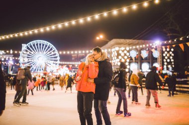 Aşık çift. Sevgililer Günü için Romantik Karakterler. Gerçek aşk. Mutlu çift akşam şehir buz pateni pistinde eğleniyor. Mutlu romantik çift buz pateni pistinde eğleniyor.