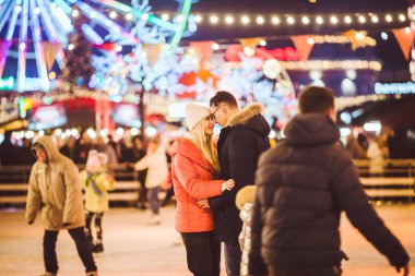 Beautiful Couple Ice Skating In City Centre. Young couple skating at a public ice skating rink outdoors. Theme ice skating rink and loving couple. Amazing winter holiday. Saint Valentines Day
