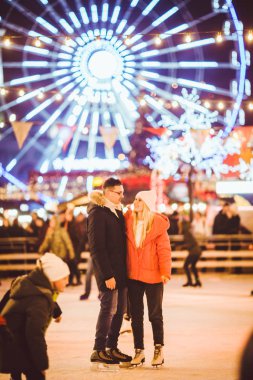 couple hugging in Saint Valentines Day. Young romantic pair having fun outdoors in winter. St. Valentines Day at city ice rink. New Year holidays. active date ice skating on ice arena on Christmas