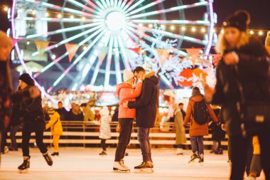 Beautiful Couple Ice Skating In City Centre. Young couple skating at a public ice skating rink outdoors. Theme ice skating rink and loving couple. Amazing winter holiday. Saint Valentines Day