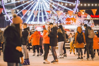 couple hugging in Saint Valentines Day. Young romantic pair having fun outdoors in winter. St. Valentines Day at city ice rink. New Year holidays. active date ice skating on ice arena on Christmas