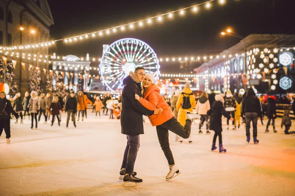 couple hugging in Saint Valentines Day. Young romantic pair having fun outdoors in winter. St. Valentines Day at city ice rink. New Year holidays. active date ice skating on ice arena on Christmas