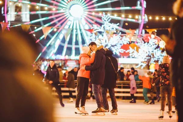 Egy pár ölelkezik Szent Valentin-napon. Fiatal romantikus pár, akik jól érzik magukat a szabadban télen. Valentin nap a városi jégpályán. Újévi ünnepek. Aktív dátum korcsolyázás a jég arénában karácsonykor — Stock Fotó