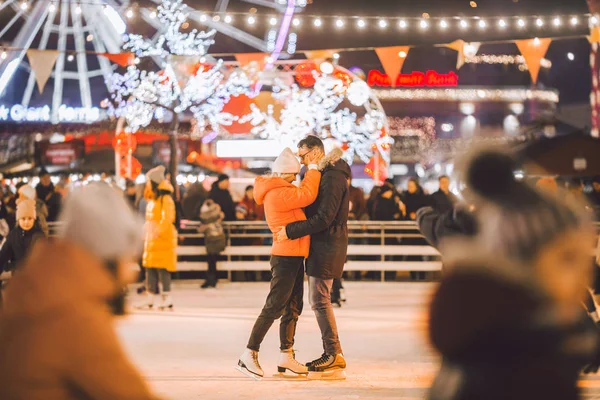 Egy pár ölelkezik Szent Valentin-napon. Fiatal romantikus pár, akik jól érzik magukat a szabadban télen. Valentin nap a városi jégpályán. Újévi ünnepek. Aktív dátum korcsolyázás a jég arénában karácsonykor — Stock Fotó