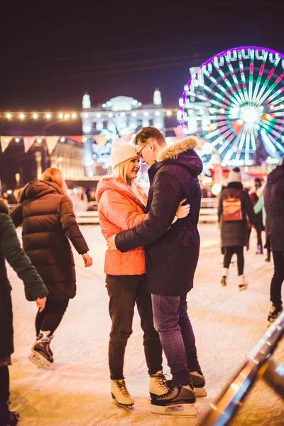 Egy pár ölelkezik Szent Valentin-napon. Fiatal romantikus pár, akik jól érzik magukat a szabadban télen. Valentin nap a városi jégpályán. Újévi ünnepek. Aktív dátum korcsolyázás a jég arénában karácsonykor — Stock Fotó