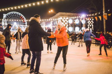 couple hugging in Saint Valentines Day. Young romantic pair having fun outdoors in winter. St. Valentines Day at city ice rink. New Year holidays. active date ice skating on ice arena on Christmas