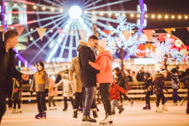 Şehir merkezinde buz pateni yapan güzel bir çift. Genç çift halka açık bir buz pateni pistinde paten kayıyor. Temalı buz pateni pisti ve sevgi dolu bir çift. İnanılmaz bir kış tatili. Sevgililer Günü