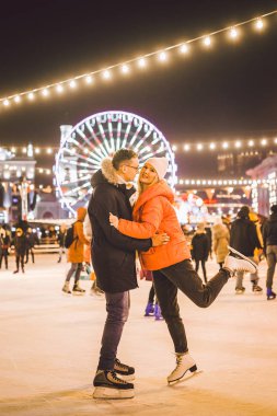 couple hugging in Saint Valentine's Day. Young romantic pair having fun outdoors in winter. St. Valentines Day at city ice rink. New Year holidays. active date ice skating on ice arena on Christmas