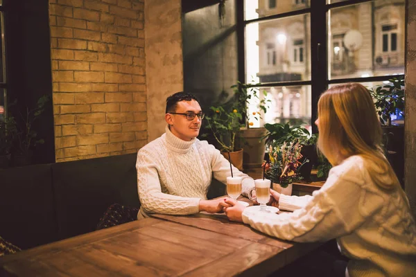 Joven pareja feliz en el amor en la cafetería, el hombre y la mujer juntos sonríen abrazándose, tomando café. Pareja hablando en Café en invierno. Pareja feliz disfrutando de un café en la cafetería. Felicidad, Navidad — Foto de Stock