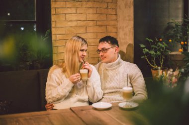 Mutlu çiftler buluşmaları ve kahve içmeleri. Aşk ve romantik randevu şehir merkezindeki kafe restoranda. Kafede aşık genç ve mutlu bir çift. Genç çift kafede buluşuyor, Noel zamanı konuşuyor ve öpüşüyor.