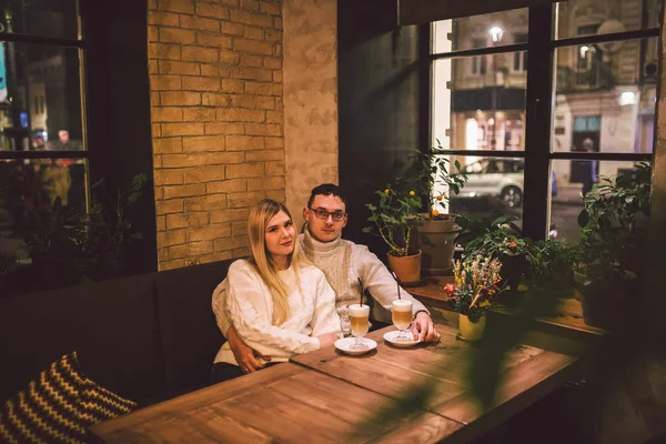 Happy Couple Meeting And Drinking Coffee. love and romantic date in downtown cafe restaurant. Young happy couple in love in cafe. Young couple date in cafe, talking and kissing at Christmas time