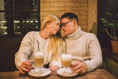 Mutlu çiftler buluşmaları ve kahve içmeleri. Aşk ve romantik randevu şehir merkezindeki kafe restoranda. Kafede aşık genç ve mutlu bir çift. Genç çift kafede buluşuyor, Noel zamanı konuşuyor ve öpüşüyor.