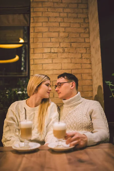 Kafede aşık genç bir çift, kadın ve erkek birlikte gülümsüyor, sarılıyor, kahve içiyor. Kışın kafede konuşan bir çift. Kahve dükkanında eğlenen mutlu çift. Mutluluk, Noel — Stok fotoğraf