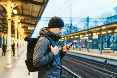 Sopot Hızlı Şehir Tren İstasyonu. Genç adam platformda ayakta ve treni bekliyor. Turistler trenle seyahat eder. Kafkas erkek portresi tren istasyonunda çekilmişti. Sırt çantalı yolcu treni bekliyor.
