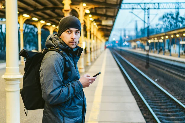 Sopot Fast Urban Railway station. young man standing and waiting train on platform. tourist travels by train. Portrait Of Caucasian Male In Railway Train Station. traveler with backpack waiting train