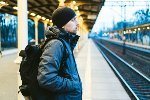 Estación de tren urbano rápido de Sopot. joven de pie y esperando tren en la plataforma. viajes turísticos en tren. Retrato de hombre caucásico en la estación de tren. viajero con mochila tren de espera — Foto de Stock