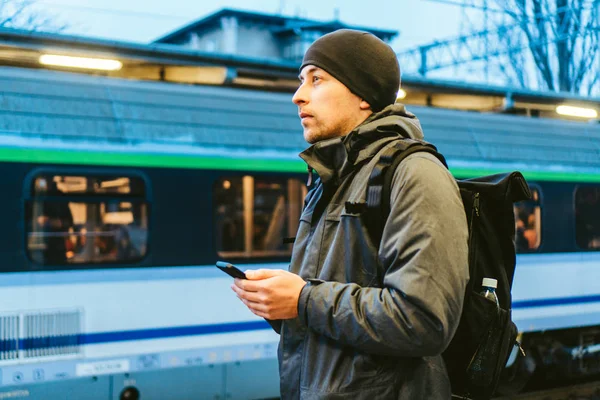 Sopot Fast Urban Railway station. young man standing and waiting train on platform. tourist travels by train. Portrait Of Caucasian Male In Railway Train Station. traveler with backpack waiting train