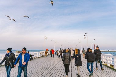 20 Temmuz 2020 'de, Baltık Denizi yakınlarındaki güneşli bir kış gününde, Polonya' nın Sopot kentindeki ahşap bir iskelede yürüyen bir kalabalık. Denize yakın bir kış tatili. Yürüyüş ve Sopot 'ta yürüyüş..