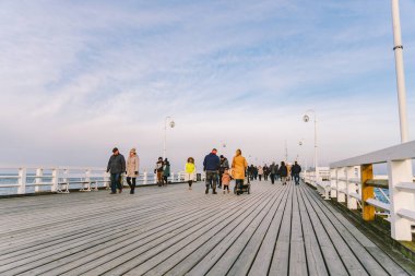 20 Temmuz 2020 'de, Baltık Denizi yakınlarındaki güneşli bir kış gününde, Polonya' nın Sopot kentindeki ahşap bir iskelede yürüyen bir kalabalık. Denize yakın bir kış tatili. Yürüyüş ve Sopot 'ta yürüyüş..
