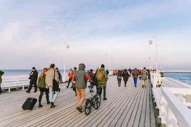 Baharda Sopot 'ta ahşap iskele. Güzel rüzgarlı hava. Sopot, Polonya 'daki eski ahşap iskelede kış günü. 9 Şubat 2020. İnsanlar Baltık Denizi yakınlarındaki güneşli kış gününde Sopot' taki ahşap iskelede yürüyorlar..