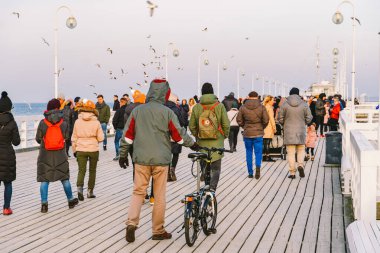 Baharda Sopot 'ta ahşap iskele. Güzel rüzgarlı hava. Sopot, Polonya 'daki eski ahşap iskelede kış günü. 9 Şubat 2020. İnsanlar Baltık Denizi yakınlarındaki güneşli kış gününde Sopot' taki ahşap iskelede yürüyorlar..