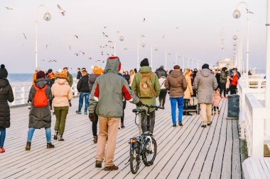 20 Temmuz 2020 'de, Baltık Denizi yakınlarındaki güneşli bir kış gününde, Polonya' nın Sopot kentindeki ahşap bir iskelede yürüyen bir kalabalık. Denize yakın bir kış tatili. Yürüyüş ve Sopot 'ta yürüyüş..