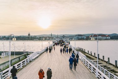 Baharda Sopot 'ta ahşap iskele. Güzel rüzgarlı hava. Sopot, Polonya 'daki eski ahşap iskelede kış günü. 9 Şubat 2020. İnsanlar Baltık Denizi yakınlarındaki güneşli kış gününde Sopot' taki ahşap iskelede yürüyorlar..