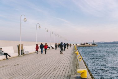 Baharda Sopot 'ta ahşap iskele. Güzel rüzgarlı hava. Sopot, Polonya 'daki eski ahşap iskelede kış günü. 9 Şubat 2020. İnsanlar Baltık Denizi yakınlarındaki güneşli kış gününde Sopot' taki ahşap iskelede yürüyorlar..