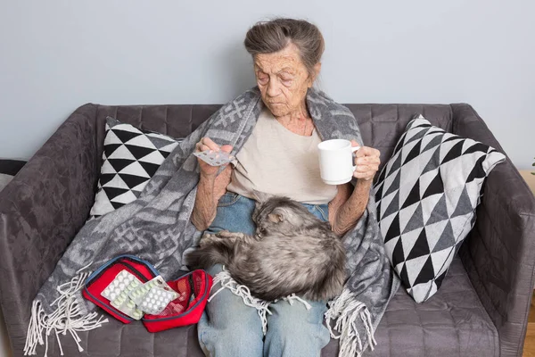 Elderly woman taking pill at home. Senior woman with her medicine tablet. ll elderly patient holding medicament pills in hands. Medicine and healthcare concept. Pharmacy, care solitude concept.