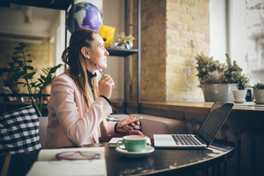 Planlama projesinde çalışan bir kadın. laptop bilgisayar, cep telefonu ve internet kullanan, çevrimiçi çalışan, modern kafede mobil uygulama ile bilgi araştıran kopyacı serbest yazar..