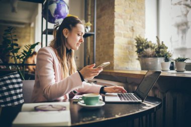 Başarılı bir iş. Dış kaynak. Kadın blogcu kafede oturur, akıllı telefon kullanır, e-postaları kontrol eder, takipçilerle iletişim kurar, haberleri okur. Serbest blog yazarı çalışıyor, her yerde iş yeri kavramı var..