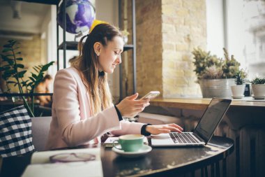Planlama projesinde çalışan bir kadın. laptop bilgisayar, cep telefonu ve internet kullanan, çevrimiçi çalışan, modern kafede mobil uygulama ile bilgi araştıran kopyacı serbest yazar..