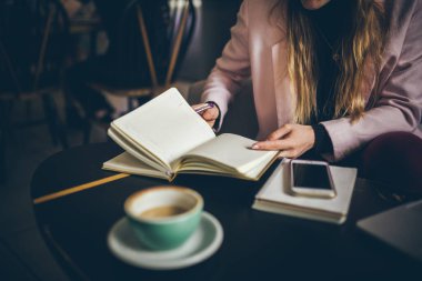 İş kadını Not Defteri Yazıyor. Defterine işaret koyan kadın ellerine yakın çekim. Şehir kahvehanesinde işyeri. Kadın işadamı öğle yemeğinde çalışıyor. Bağımsız blog yazarı gazeteci iş başında