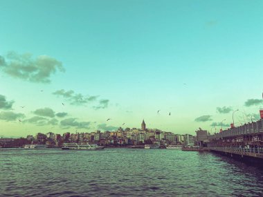 İstanbul 'daki İstanbul Boğazı' ndaki Galata Köprüsü ve Galata Kulesi. İstanbul birçok martıya ve bulutlu gökyüzüne sahiptir. Karaköy bölgesi ve Altın Boynuz.
