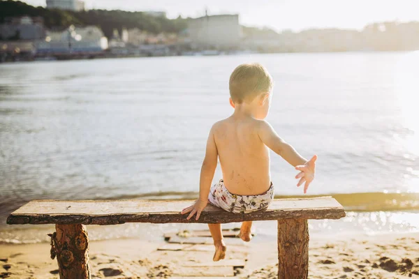 Niño Sentado Banco Madera Con Espalda Playa Cerca Del Agua —  Fotos de Stock