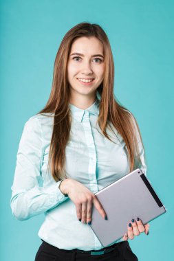 Her zaman bağlanırdı. Dijital tablet bilgisayar kullanan bir kadın turkuaz arka planda mutlu bir şekilde izole edilmiş. Kafkasyalı genç kadın işçi, öğretmen, elinde tabletle gömlek ofisi tarzında akıl hocalığı yapıyor.