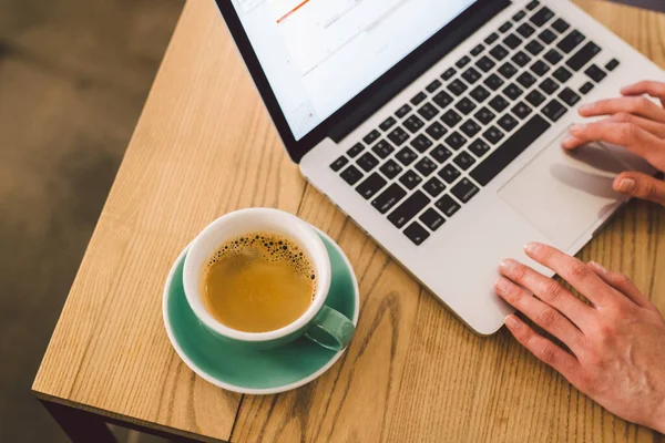 クローズアップビジネスウーマンは カップコーヒーとラップトップを使用して手 喫茶店でキーボードコンピュータを入力する女性の手 テーブルの中のスマートフォンとホットカップカプチーノ 人々のライフスタイルの概念 フリーランスのテーマ — ストック写真
