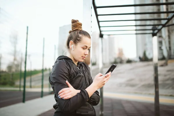 女运动员通过手机应用于健身活动追踪器心率监测器跟踪智能手机上的健康进展情况 运动与健康 戴耳机的白人年轻女运动员 — 图库照片